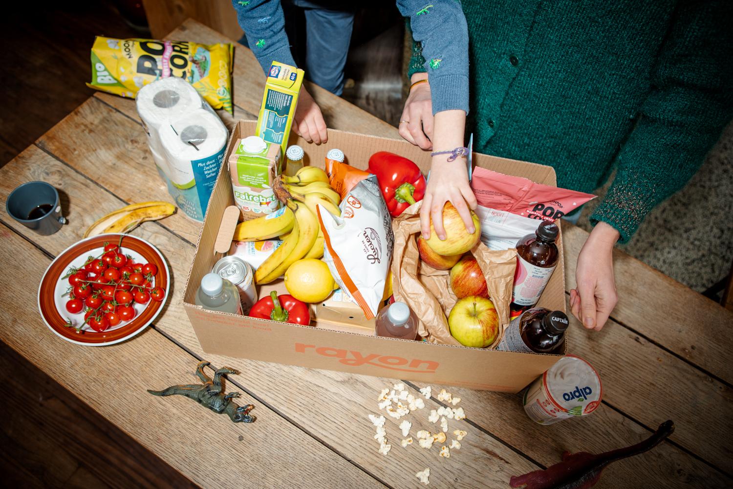 A birds eye view of two people exploring a box of fresh food delivered by Rayon