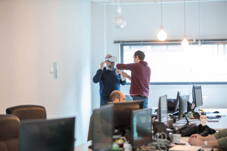 Two engineers in a large office interacting with a VR device